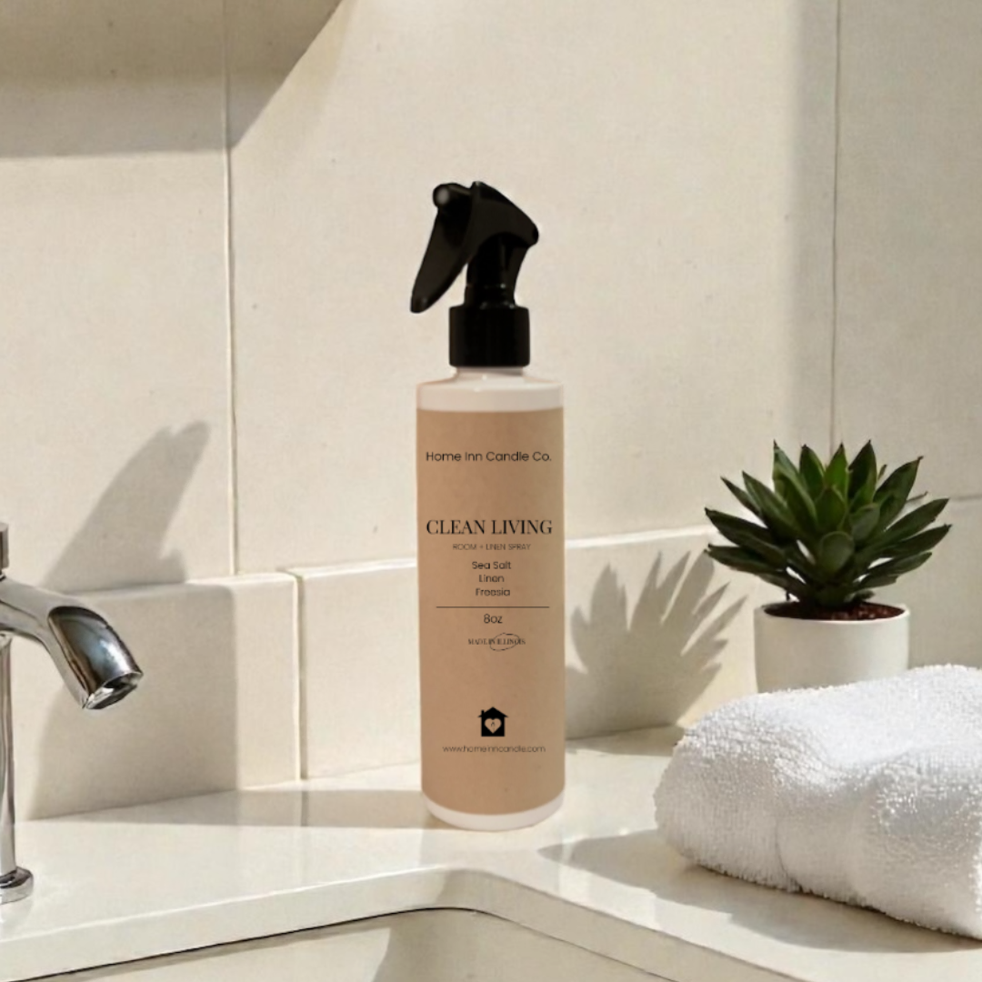 Room Spray Labeled Clean Living by Home Inn Candle on a bathroom counter with sink and towel in the background
