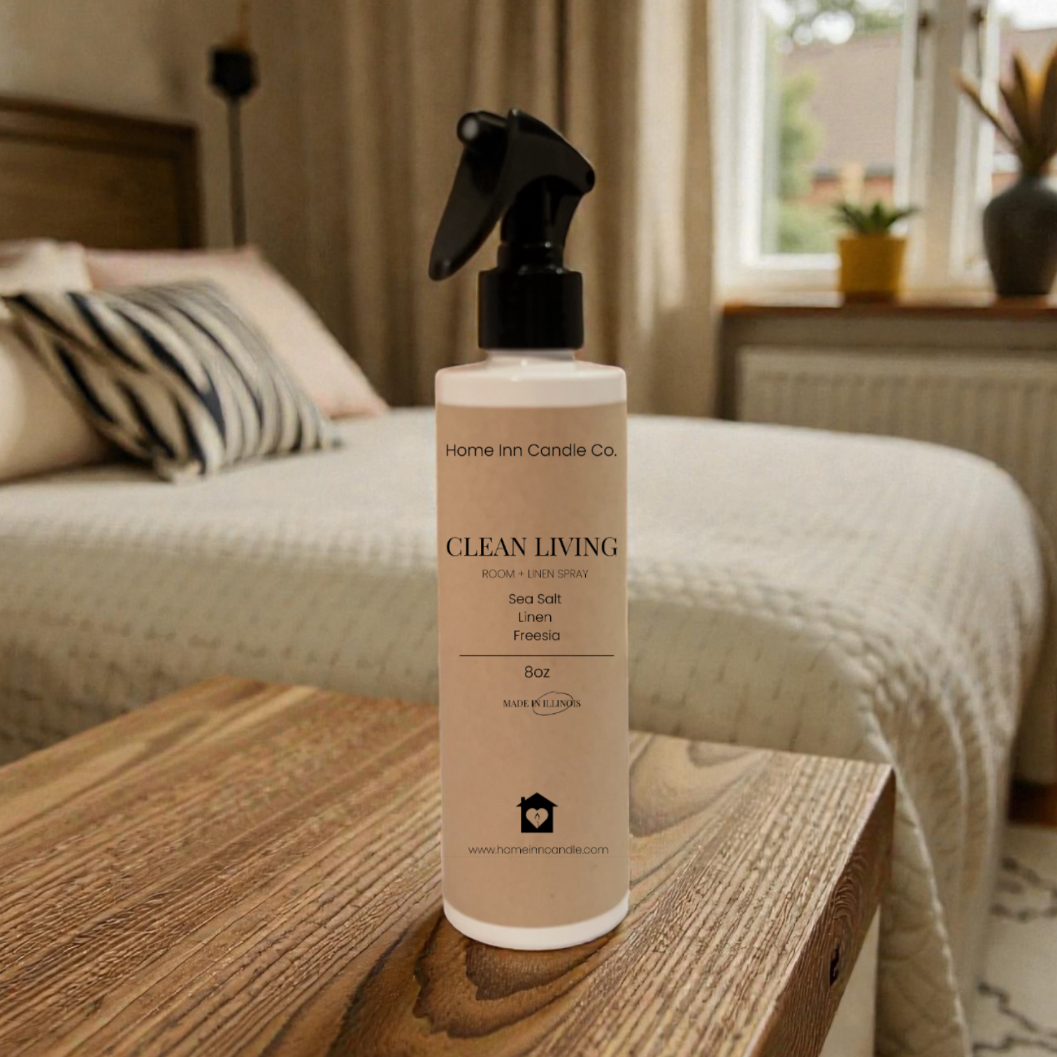 Home Fragrance room spray bottle labeled 'Clean Living' by Home Inn Candle on a wooden surface with a bedroom in the background