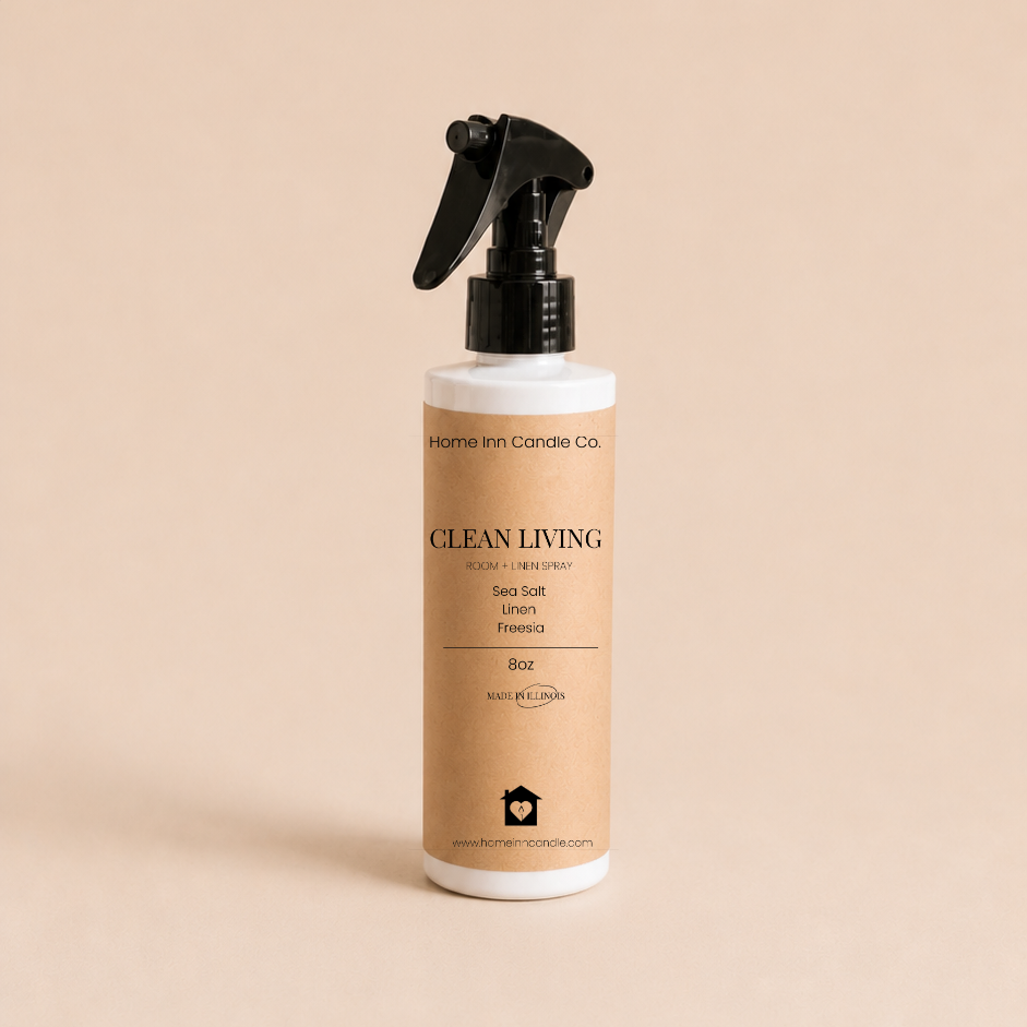 A bottle of Clean Living Room Spray by Home Inn Candle Co.  with a black trigger sprayer and a beige label, set against a solid beige background.