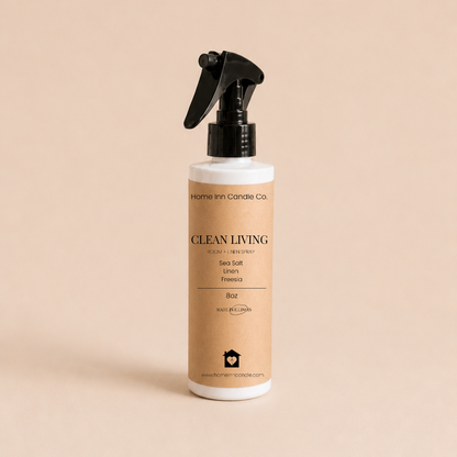 A bottle of Clean Living Room Spray by Home Inn Candle Co.  with a black trigger sprayer and a beige label, set against a solid beige background.