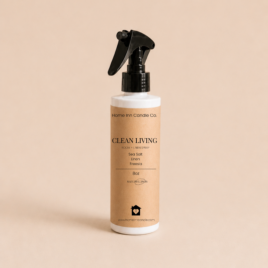 A bottle of Clean Living Room Spray by Home Inn Candle Co.  with a black trigger sprayer and a beige label, set against a solid beige background.