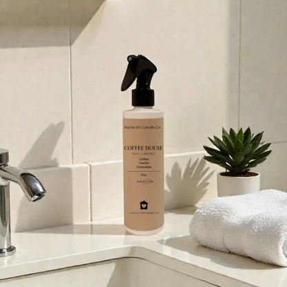 Bottle of home inn candle room spray on a bathroom counter with sink and towel in the background