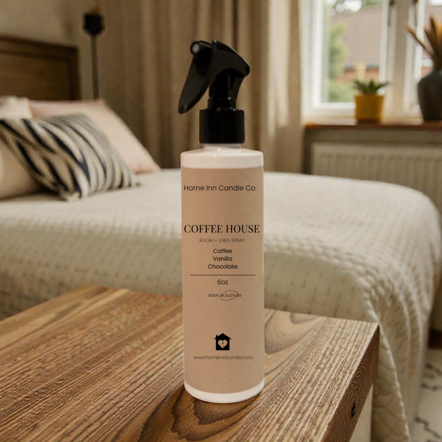 Bottle of Home Inn Candle 'Coffee House' room spray on a wooden table in a bedroom.