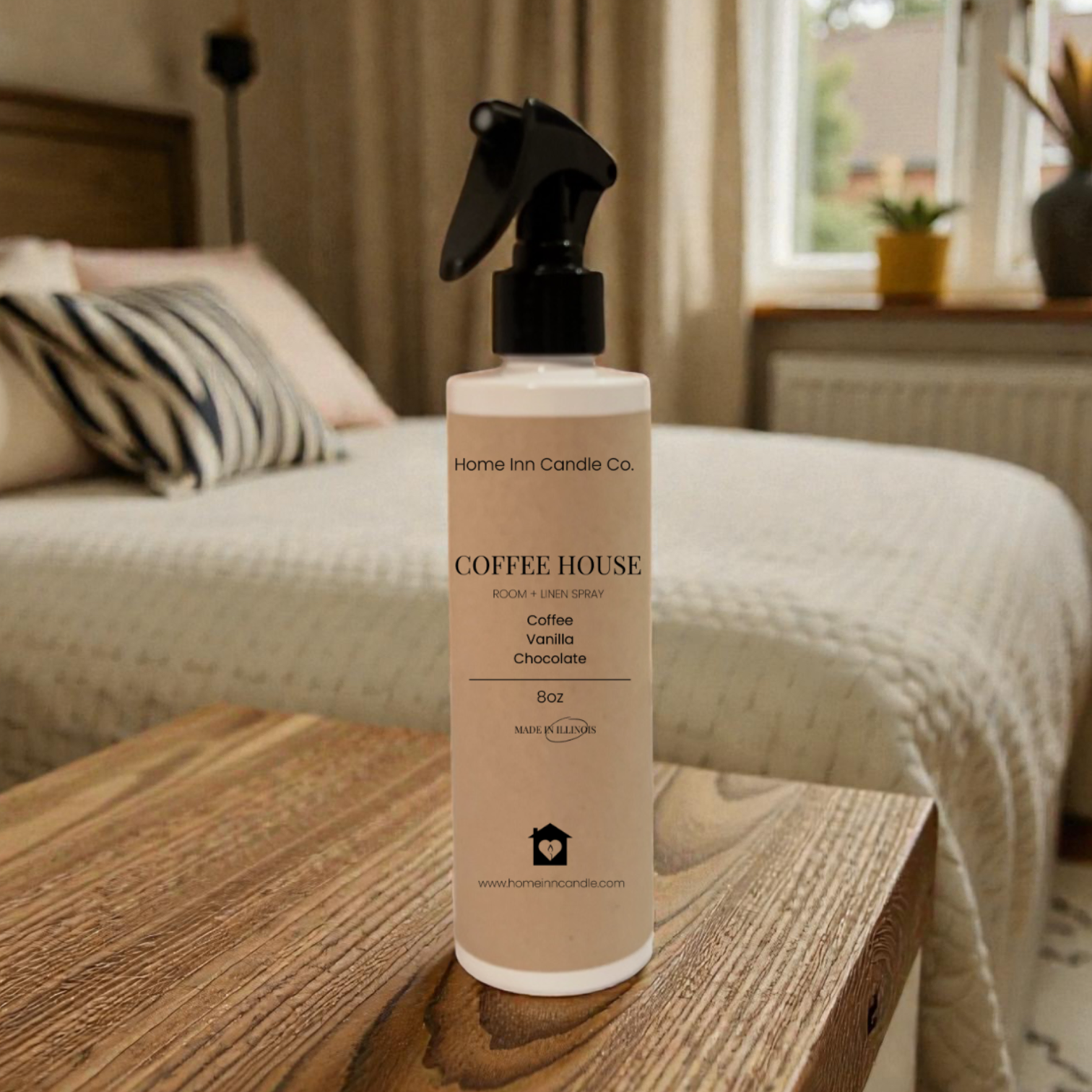 Bottle of Home Inn Candle 'Coffee House' room spray on a wooden table in a bedroom.