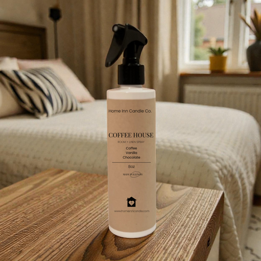 Bottle of Home Inn Candle 'Coffee House' room spray on a wooden table in a bedroom.