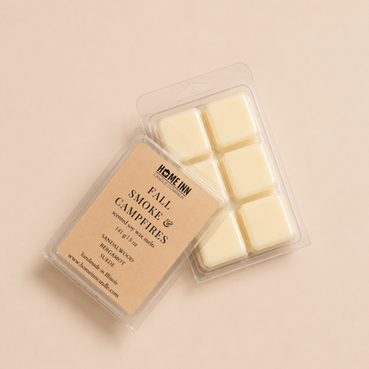 A wax melt package labeled 'HOME INN CANDLE FALL SMOKE AND CAMPFIRES ' on a warm beige background. The clear plastic clamshell contains six off-white wax cubes, with the beige paper label visible on top.