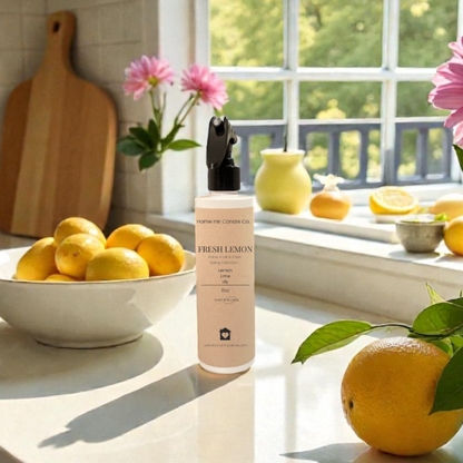 Kitchen counter with lemons, a Fresh Lemon Room Spray from Home Inn Candle, and flowers near a window.