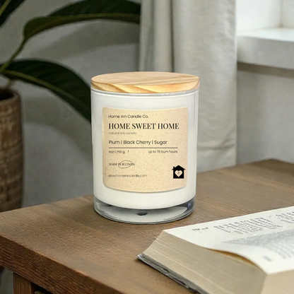 Candle labeled 'Home Sweet Home' on a wooden surface with an open book and plant in the background