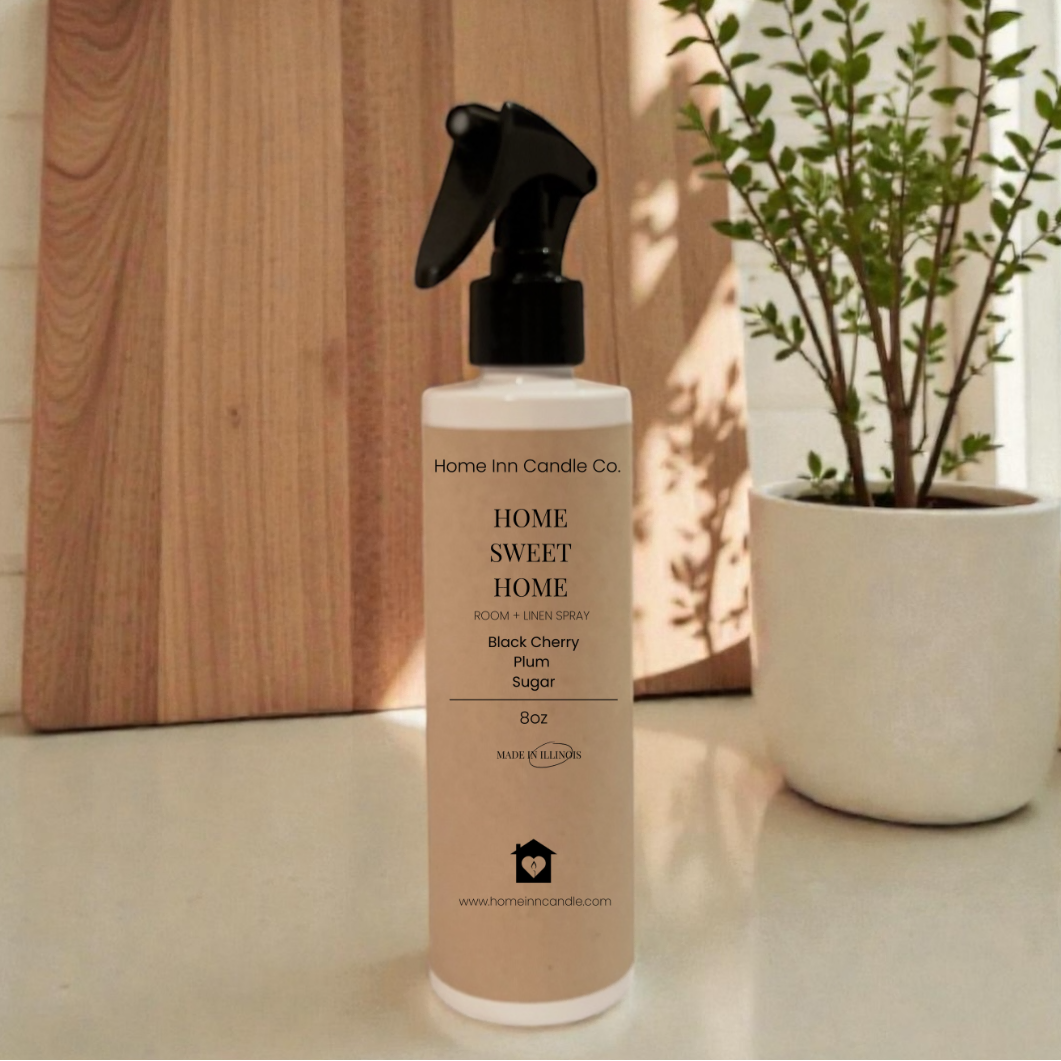 Room Spray bottle labeled 'Home Sweet Home' by Home Inn Candle on a kitchen counter with a cutting board and plant in the background.