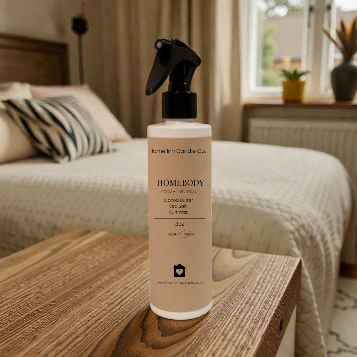 Homebody room spray by Home Inn Candle  on a wooden surface with a bedroom in the background