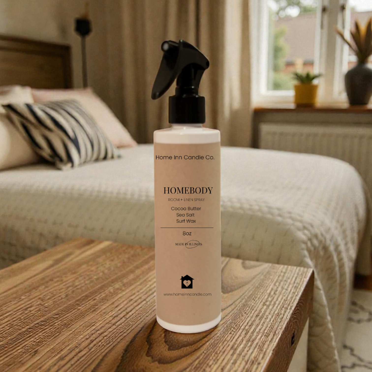 Homebody room spray by Home Inn Candle  on a wooden surface with a bedroom in the background
