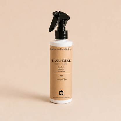 A bottle of Lake House Room Spray from Home Inn Candle Co. Sea Salt scented featuring a beige label and black spray nozzle, set against a solid beige background.