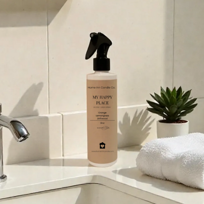 My Happy Place Room Spray from Home Inn Candle on a bathroom counter with sink and towel in the background