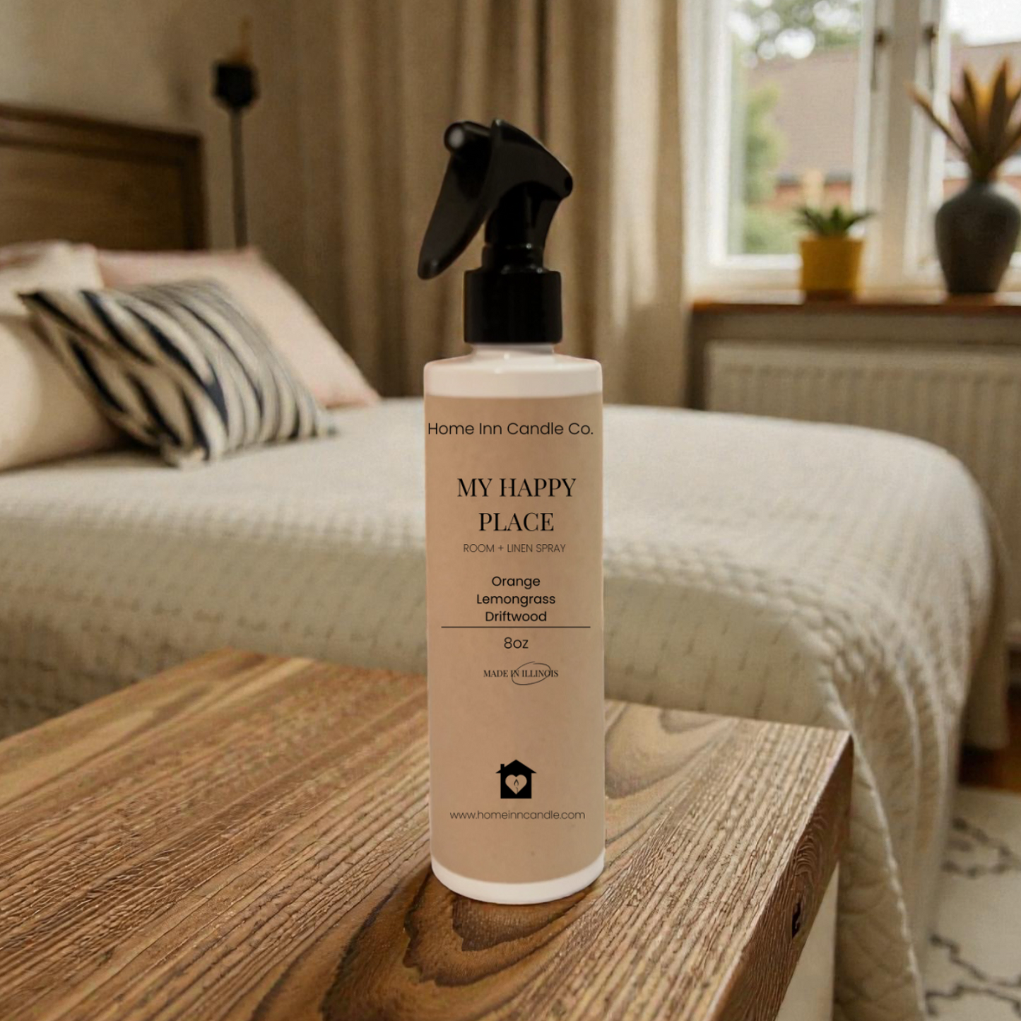 Spray bottle labeled 'My Happy Place' from Home Inn Candle on a wooden surface with a bedroom in the background