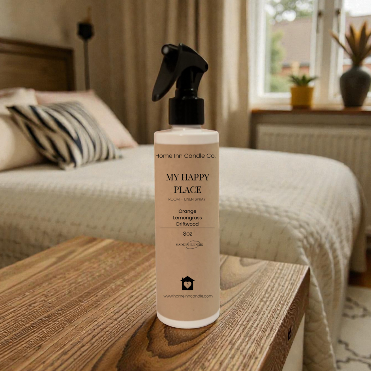 Spray bottle labeled 'My Happy Place' from Home Inn Candle on a wooden surface with a bedroom in the background