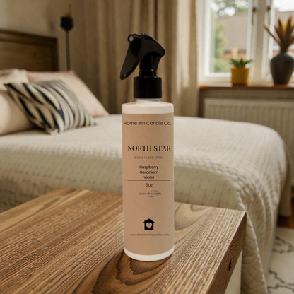 Bottle of Home Inn Candle 'North Star' room spray on a wooden surface with a bedroom in the background