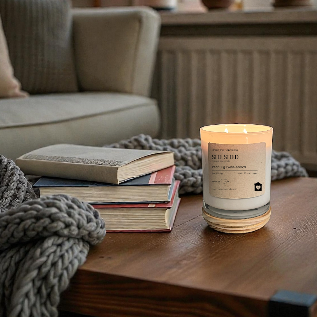 Candle on a wooden table in a cozy living room with books and a blanket.