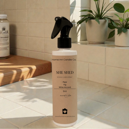  'She Shed' Room Spray by Home Inn Candle  on a windowsill with plants and a tiled wall in the background