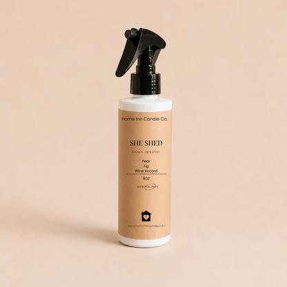 A bottle of She Shed Room spray from Home Inn Candle with a black trigger sprayer and a beige label, set against a solid beige background.