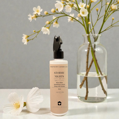 Stormy Nights room spray from Home Inn Candle Co on a white surface with a floral arrangement in a vase