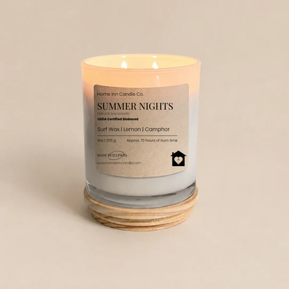 A lit scented candle in a clear glass jar with a cream-colored label reading 'Summer Nights' from Home Inn Candle