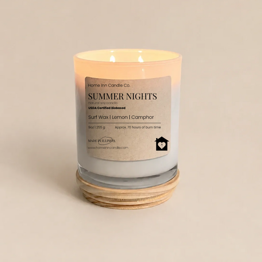A lit scented candle in a clear glass jar with a cream-colored label reading 'Summer Nights' from Home Inn Candle