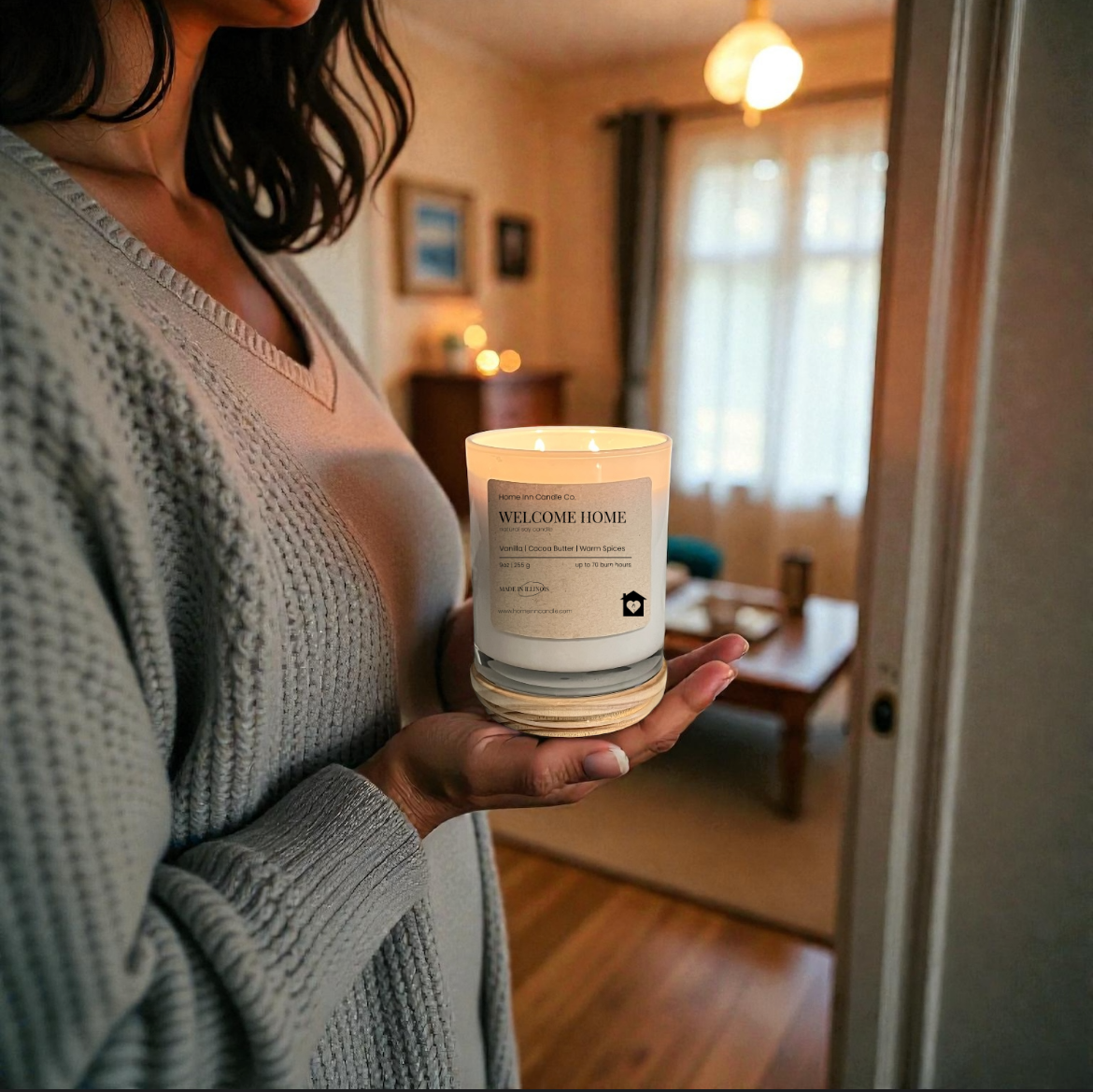 Person holding a 'Welcome Home' candle in a cozy living room.