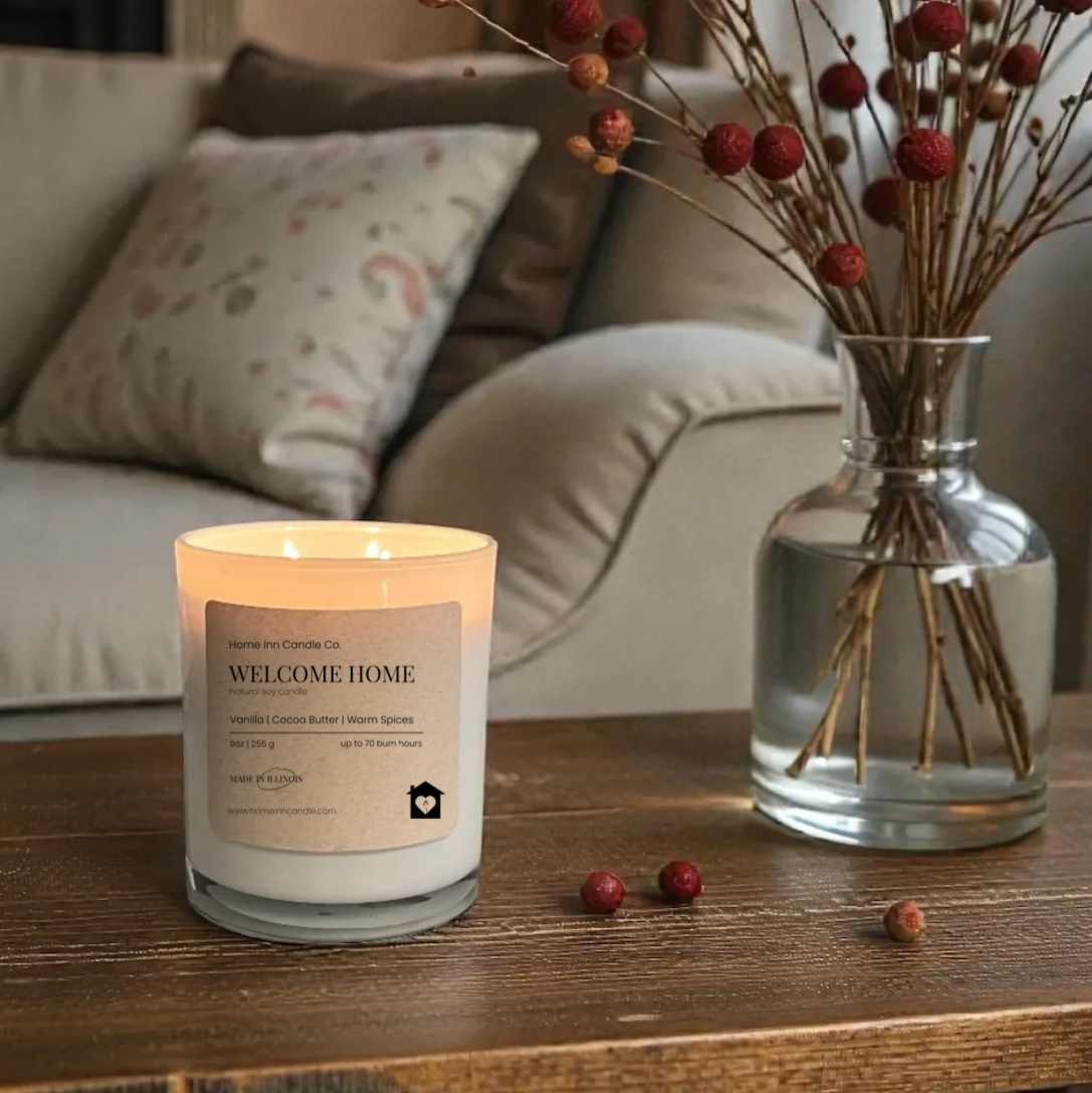 Candle labeled 'Welcome Home' on a table with decorative elements in a cozy living room.