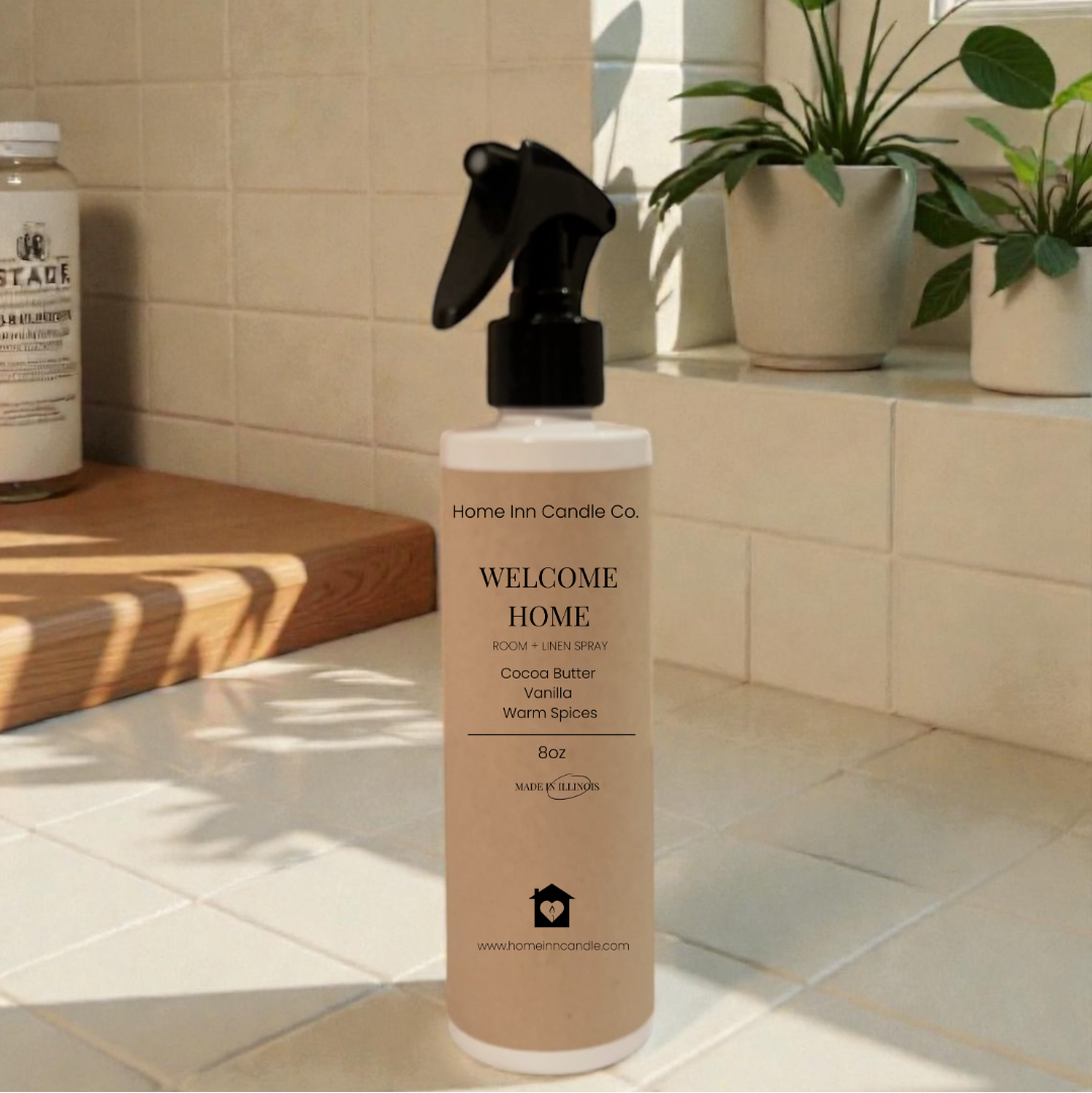 Bottle of 'Welcome Home' room spray by Home Inn Candle on a windowsill with plants and a tiled wall in the background